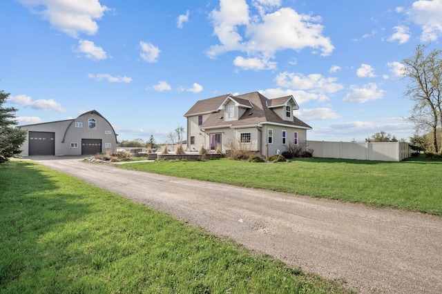 view of front of home featuring a garage, fence, an outbuilding, and a front yard