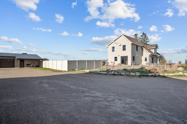 view of side of property with fence and dirt driveway