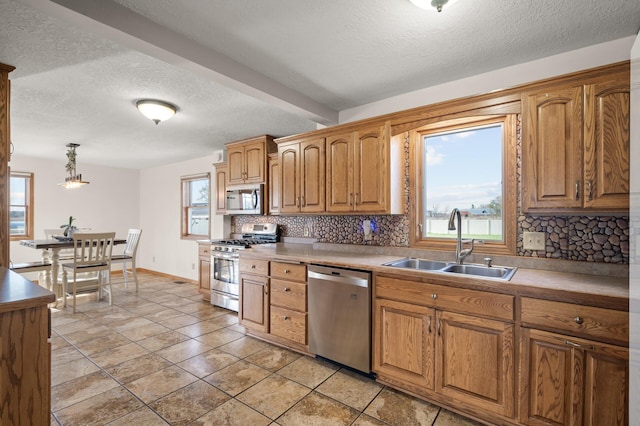 kitchen featuring a sink, appliances with stainless steel finishes, decorative backsplash, and plenty of natural light
