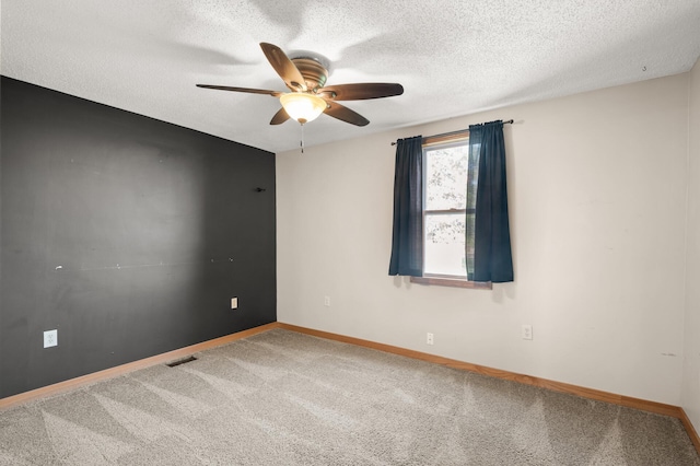 carpeted empty room with a ceiling fan, a textured ceiling, visible vents, and baseboards