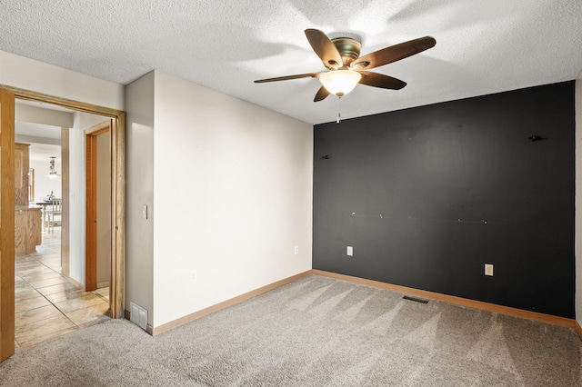 empty room with visible vents, baseboards, ceiling fan, and light carpet
