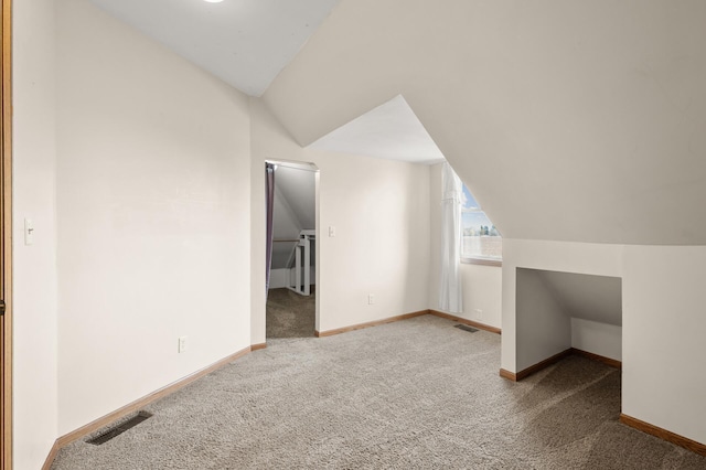 additional living space featuring carpet floors, visible vents, and lofted ceiling