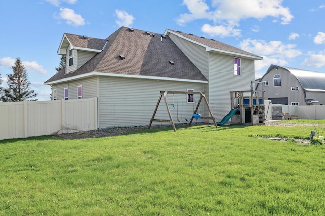 back of property with a playground, fence, a lawn, and roof with shingles