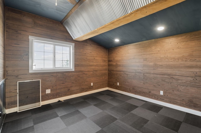 spare room featuring baseboards, wooden walls, and dark floors