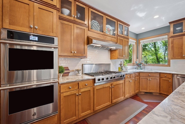 4970 Yuma Ct N, Plymouth, MN 55446 - kitchen with stainless steel appliances, under cabinet range hood, dark wood-style flooring, decorative backsplash, and light stone countertops