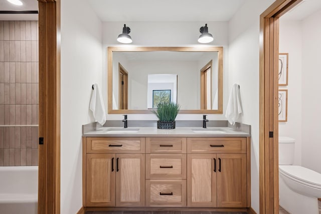full bath featuring double vanity, toilet, a bathing tub, and a sink
