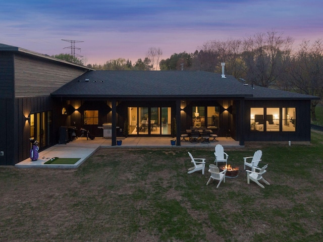 back of house at dusk with an outdoor fire pit, a patio area, and a lawn