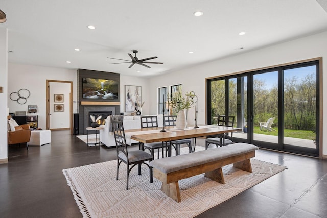 dining room featuring recessed lighting, baseboards, ceiling fan, concrete floors, and a large fireplace