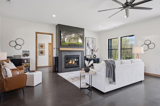 living area with concrete flooring, recessed lighting, a large fireplace, ceiling fan, and baseboards