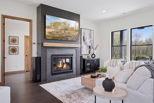 living area with baseboards, concrete flooring, recessed lighting, and a large fireplace
