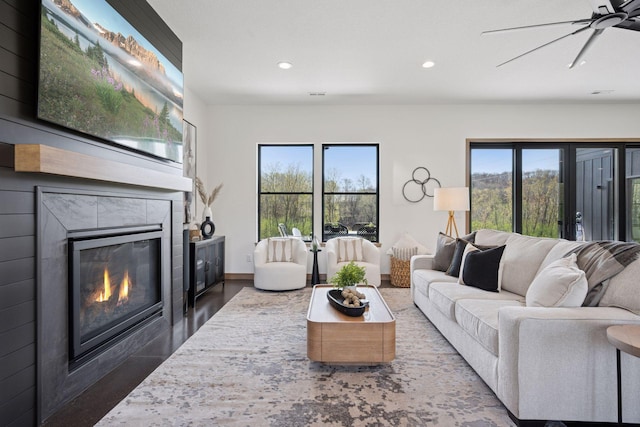 living room featuring ceiling fan, baseboards, a tiled fireplace, and recessed lighting