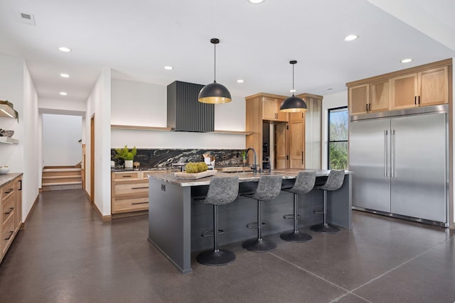 kitchen featuring light stone countertops, a sink, recessed lighting, and stainless steel built in refrigerator
