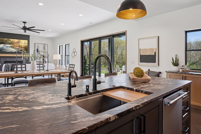 kitchen featuring recessed lighting, a healthy amount of sunlight, dark stone countertops, and a sink