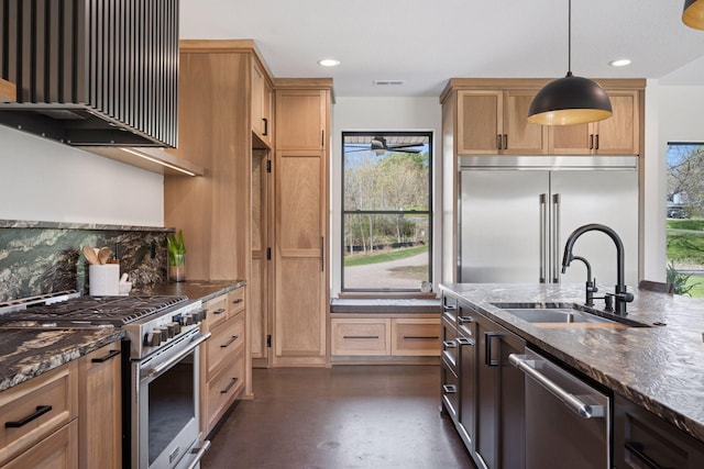 kitchen featuring concrete floors, dark stone countertops, a sink, wall chimney exhaust hood, and stainless steel appliances