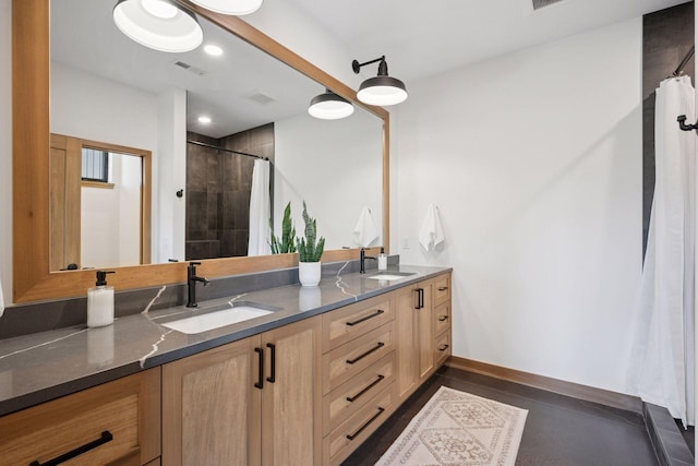 full bathroom with a sink, double vanity, visible vents, and a tile shower