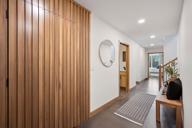 hallway with baseboards, recessed lighting, and concrete flooring