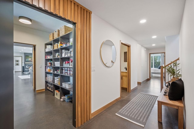 hallway featuring concrete floors, baseboards, and recessed lighting