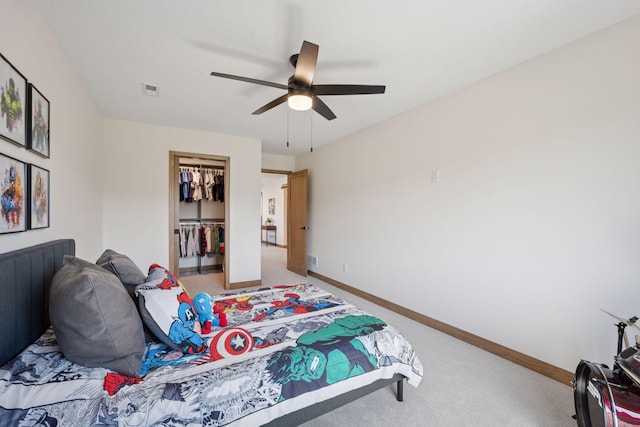 bedroom with a closet, a walk in closet, baseboards, ceiling fan, and light colored carpet