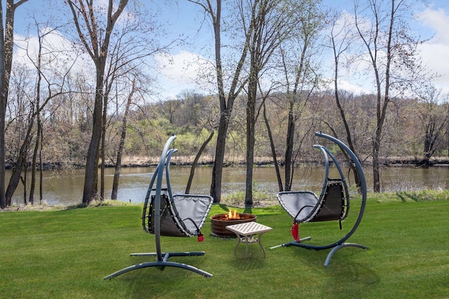 surrounding community featuring a lawn, a water view, and an outdoor fire pit