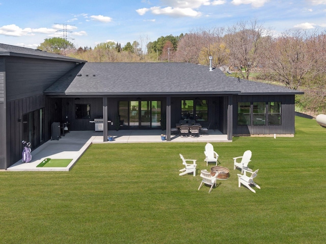 back of property featuring a fire pit, a shingled roof, a patio, and a lawn