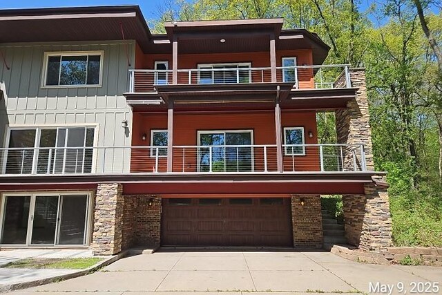 21 Red Fox Rd, North Oaks, MN 55127 - view of front facade featuring a balcony, a garage, driveway, and stone siding
