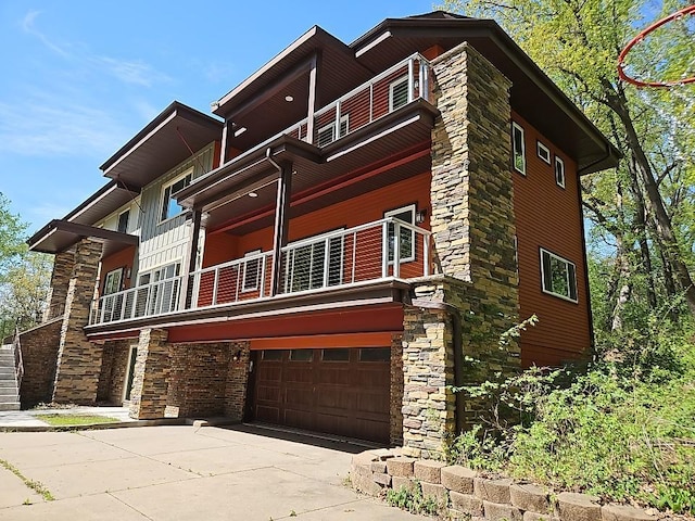 21 Red Fox Rd, North Oaks, MN 55127 - view of front facade featuring a balcony, an attached garage, driveway, and stone siding