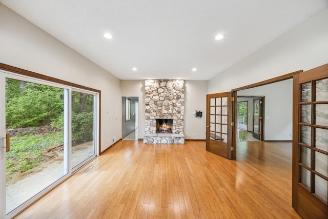 21 Red Fox Rd, North Oaks, MN 55127 - unfurnished living room featuring healthy amount of natural light, french doors, a fireplace, light wood-style floors, and recessed lighting