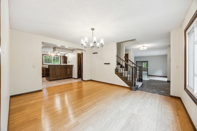 21 Red Fox Rd, North Oaks, MN 55127 - empty room featuring a chandelier, light wood finished floors, stairway, baseboards, and a textured ceiling