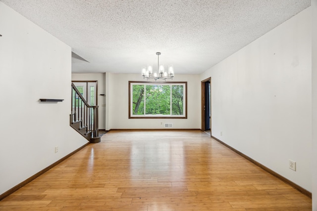 21 Red Fox Rd, North Oaks, MN 55127 - unfurnished room featuring a chandelier, a textured ceiling, light wood-style floors, stairs, and baseboards