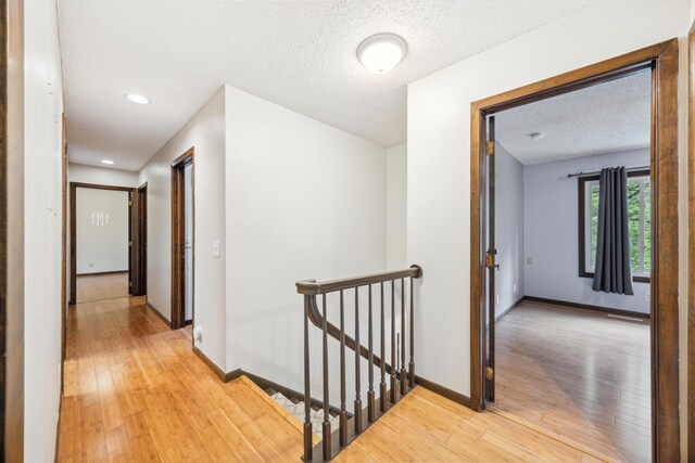 21 Red Fox Rd, North Oaks, MN 55127 - hallway featuring an upstairs landing, light wood finished floors, baseboards, a textured ceiling, and recessed lighting