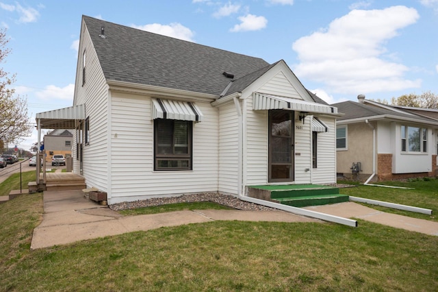view of front facade with a shingled roof and a front yard
