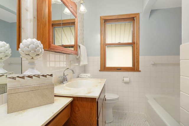 bathroom with tile walls, a wainscoted wall, tile patterned floors, toilet, and a tub to relax in
