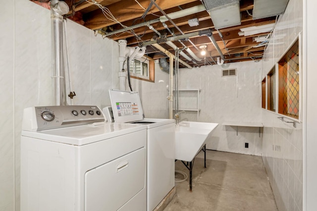 washroom featuring washer and dryer, laundry area, visible vents, and a sink
