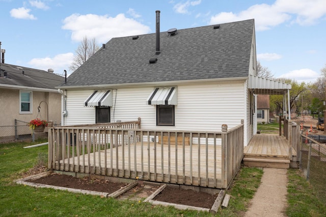 rear view of property with roof with shingles, fence, a wooden deck, and a lawn
