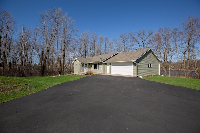 single story home featuring an attached garage, roof with shingles, driveway, and a front yard