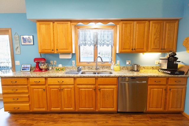 kitchen with stainless steel dishwasher, brown cabinetry, dark wood-style flooring, light stone countertops, and a sink