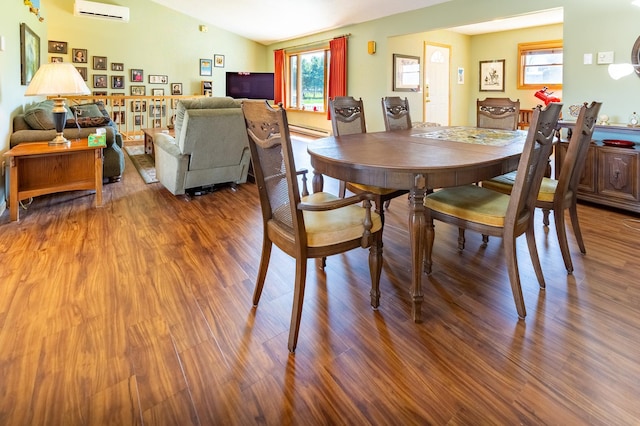 dining area featuring plenty of natural light, a wall unit AC, a baseboard heating unit, and wood finished floors