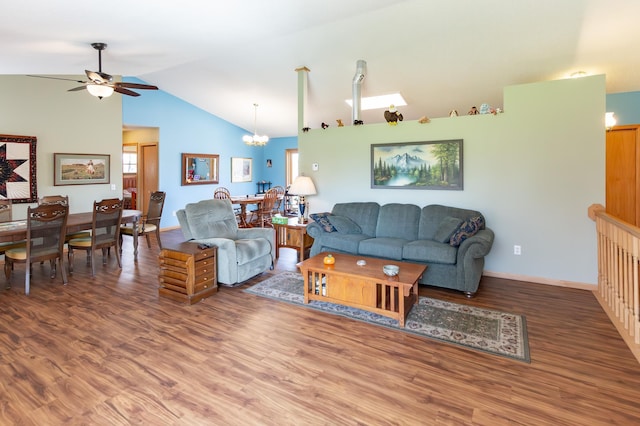 living room with baseboards, ceiling fan with notable chandelier, wood finished floors, and vaulted ceiling