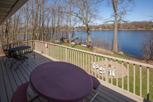 wooden deck with a lawn, outdoor dining area, and a water view