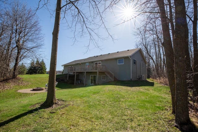back of property featuring stairway, a deck, a yard, and a fire pit