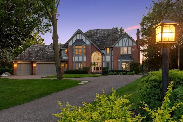 1510 Green Trees Rd, Orono, MN 55391 - tudor-style house with an attached garage, a chimney, a lawn, concrete driveway, and brick siding