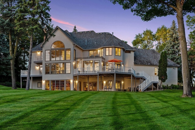 1510 Green Trees Rd, Orono, MN 55391 - back of property at dusk with stucco siding, a lawn, stairway, and a balcony