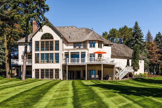 1510 Green Trees Rd, Orono, MN 55391 - back of property featuring stucco siding, a balcony, a chimney, a lawn, and stairway