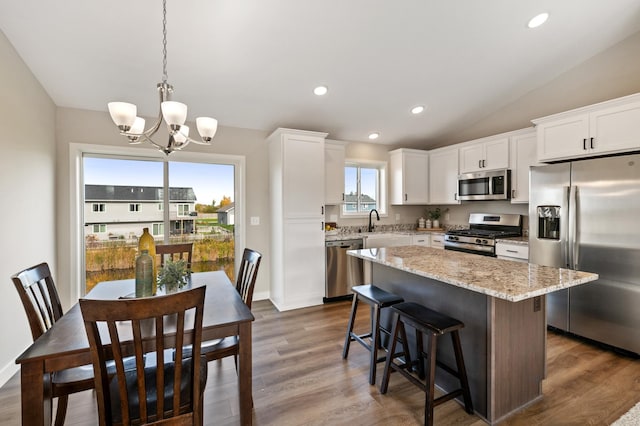 kitchen featuring white cabinets, light stone countertops, an inviting chandelier, a center island, and stainless steel appliances