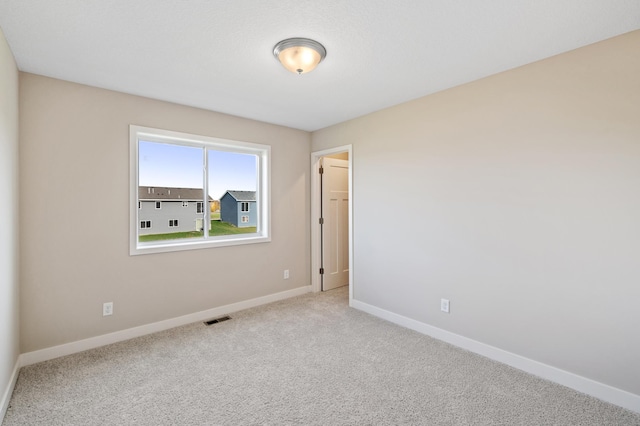 spare room with carpet flooring, baseboards, and visible vents