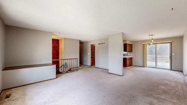 empty room with light carpet, baseboards, and a textured ceiling