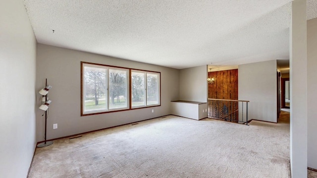 empty room with a textured ceiling, carpet floors, and a chandelier