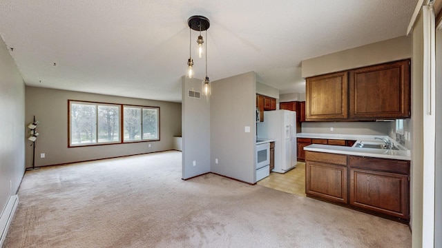 kitchen featuring white appliances, light carpet, light countertops, open floor plan, and hanging light fixtures