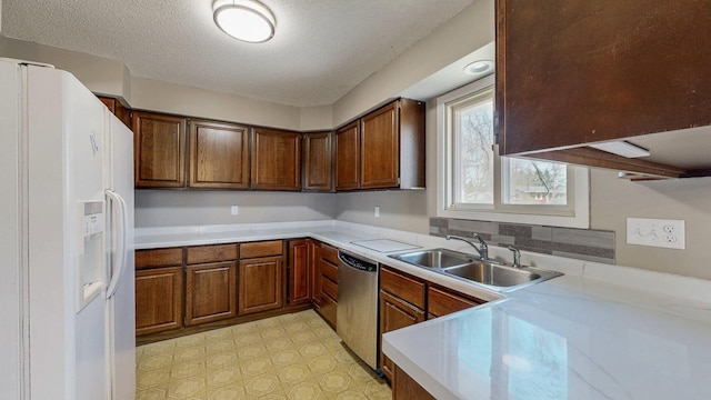 kitchen with a sink, stainless steel dishwasher, white fridge with ice dispenser, light countertops, and a textured ceiling