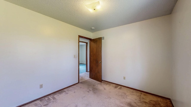 unfurnished room featuring light colored carpet, baseboards, and a textured ceiling